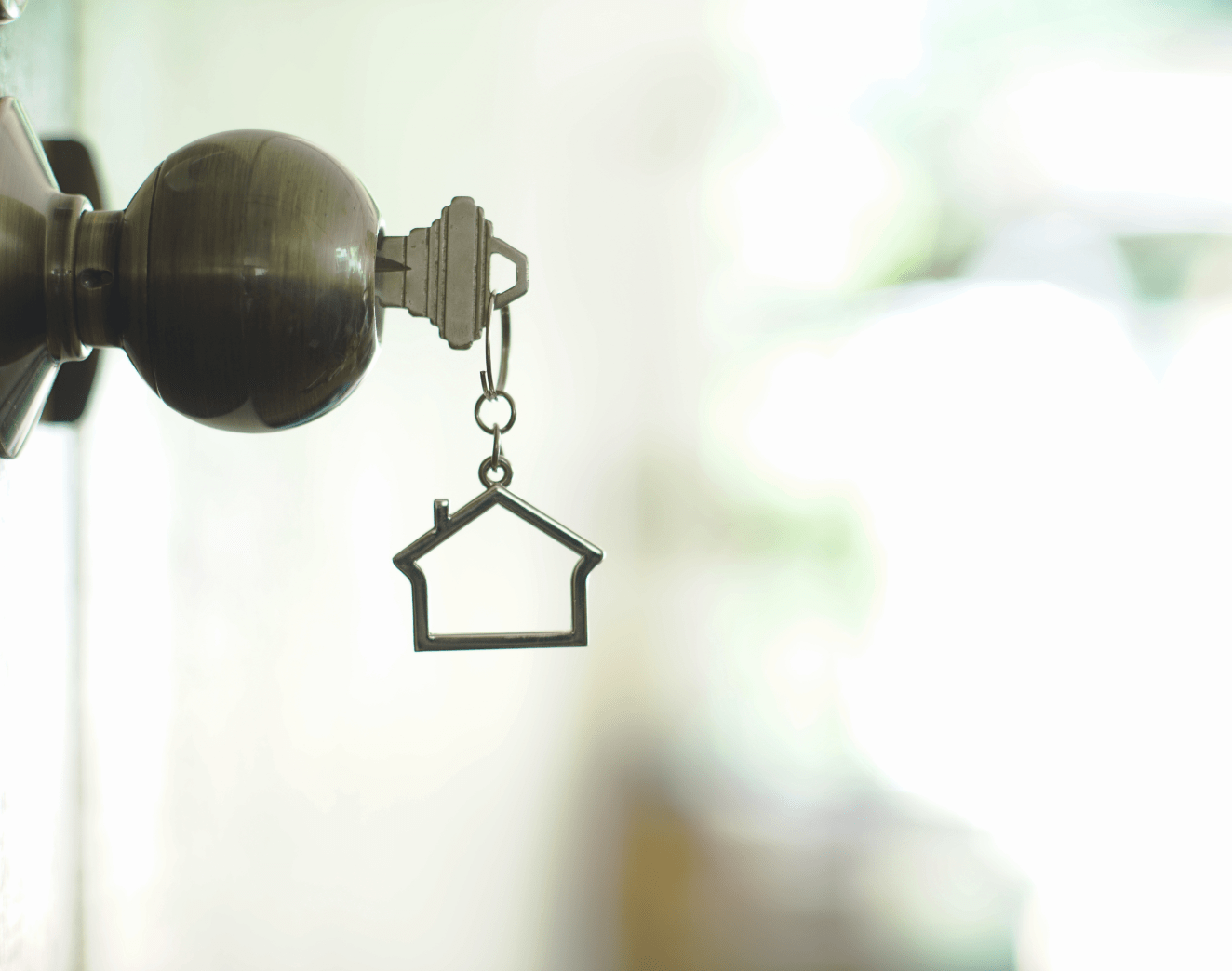 House keychain hanging from a key in the door