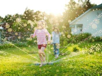 June 2023 Market Stats children playing in a backyard sprinkler
